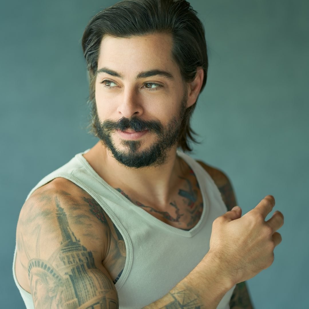 A man, celebrity hairstylist Michael Due&ntilde;as, wearing a white tank top with tattoos.