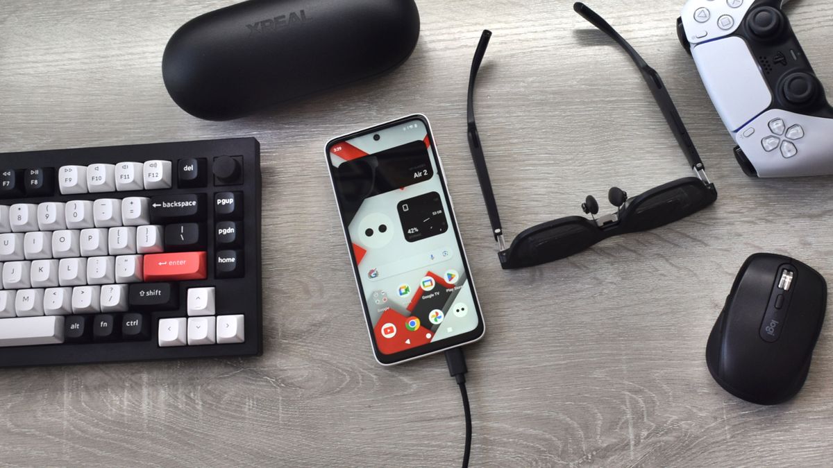 XREAL Beam Pro and XREAL Air 2 AR smart glasses on a desk with a Bluetooth keyboard, mouse, and game controller