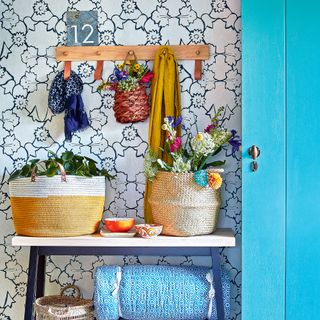 Hallway with patterned wallpaper, flowers in baskets and blue door