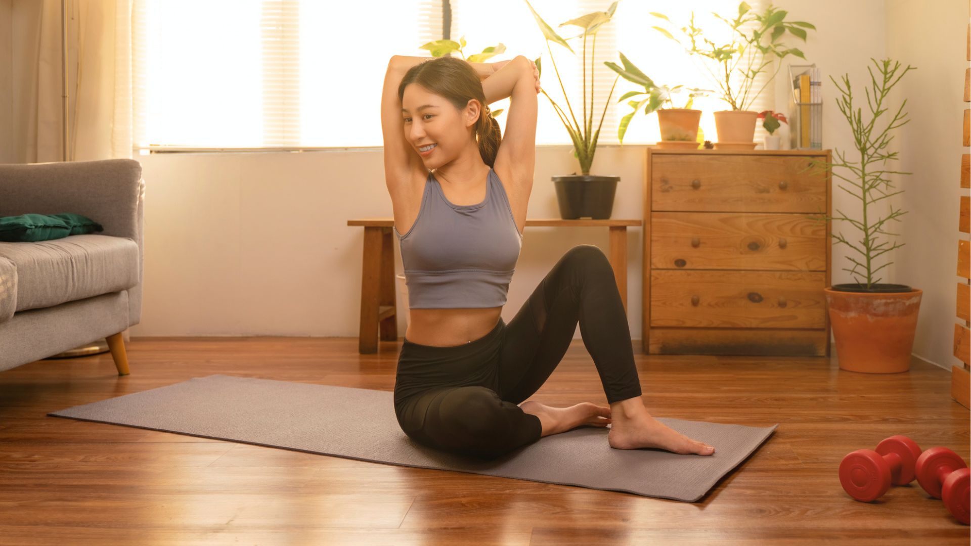 woman sits on yoga mat doing a triceps stretch