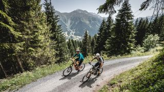 Two e-MTB riders climbing up a gravel track in Switzerland