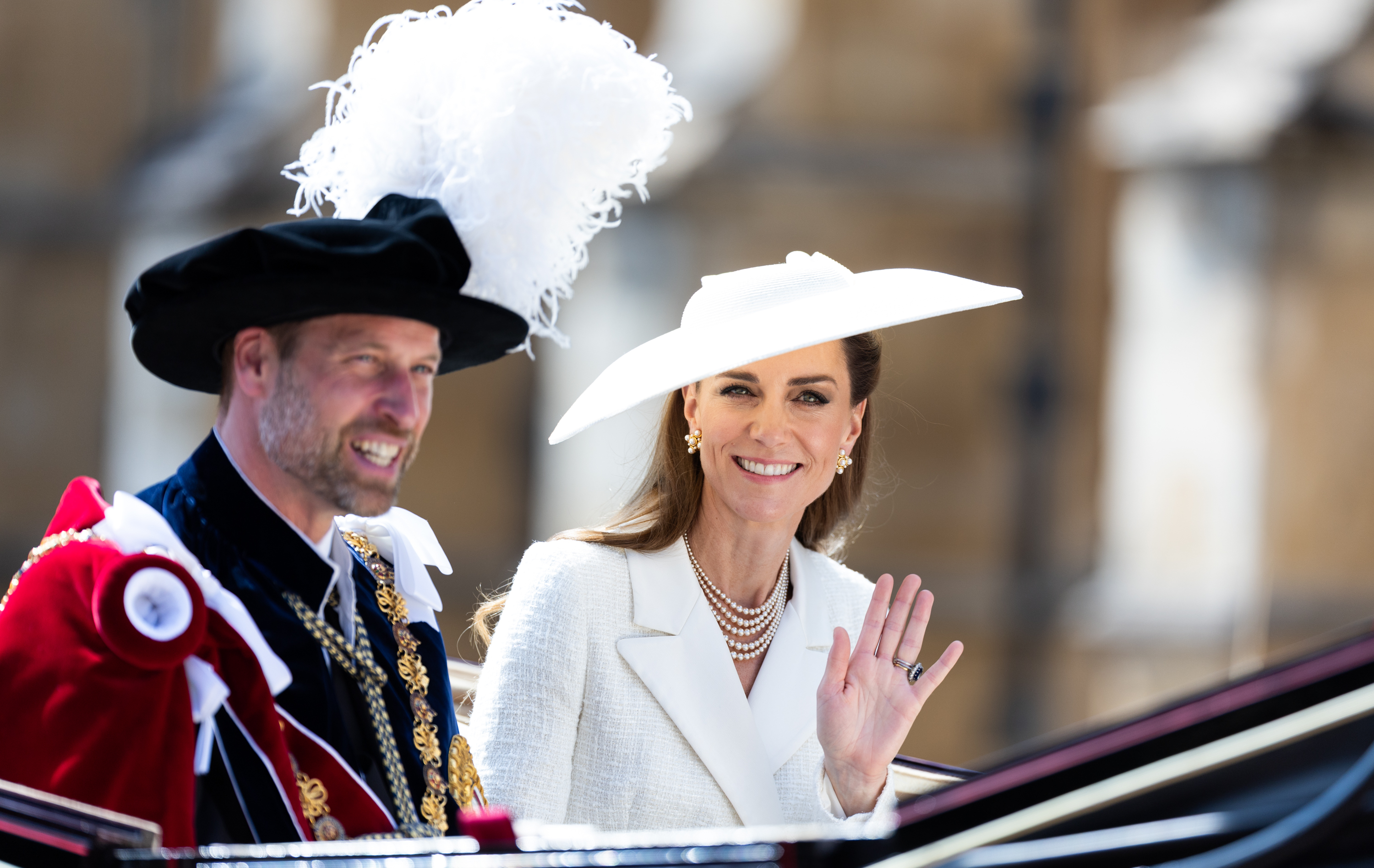 Prince William and Princess Kate smiling and waving in a carriage