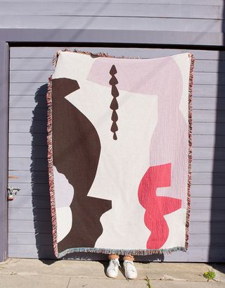 Brown, pink and white woven blanket being held up