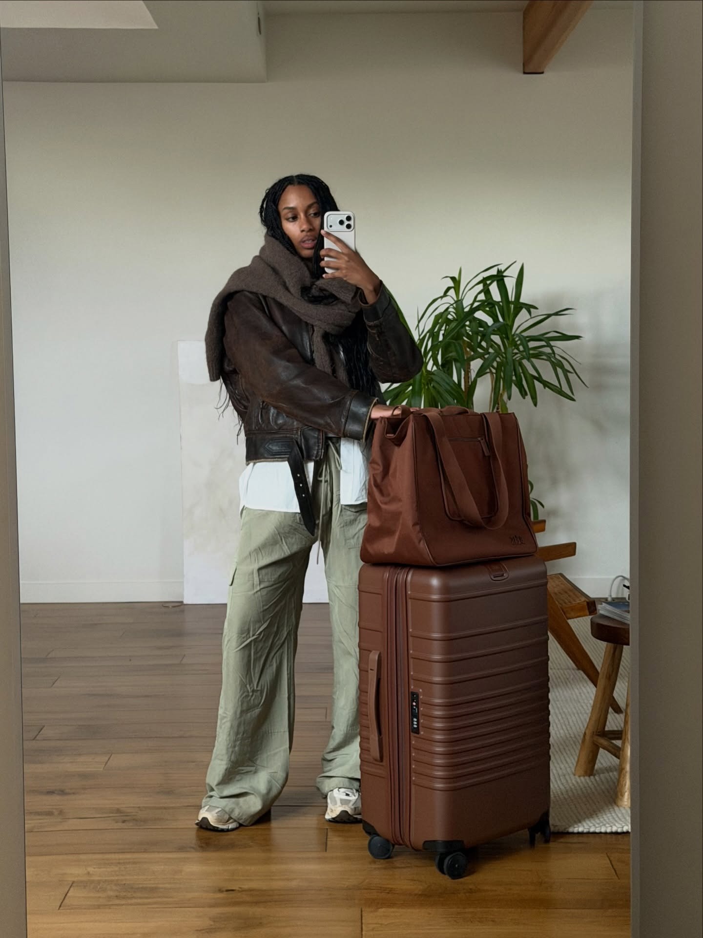 French woman wearing a travel outfit that includes a leather jacket, army green pants, and sneakers