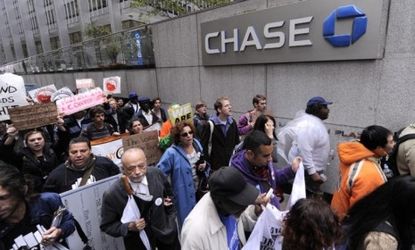 Occupy Wall Street protesters walk by the J.P. Morgan Chase building in New York City: Large banks, including Chase, are backing off highly unpopular debit card fees, perhaps because of the O