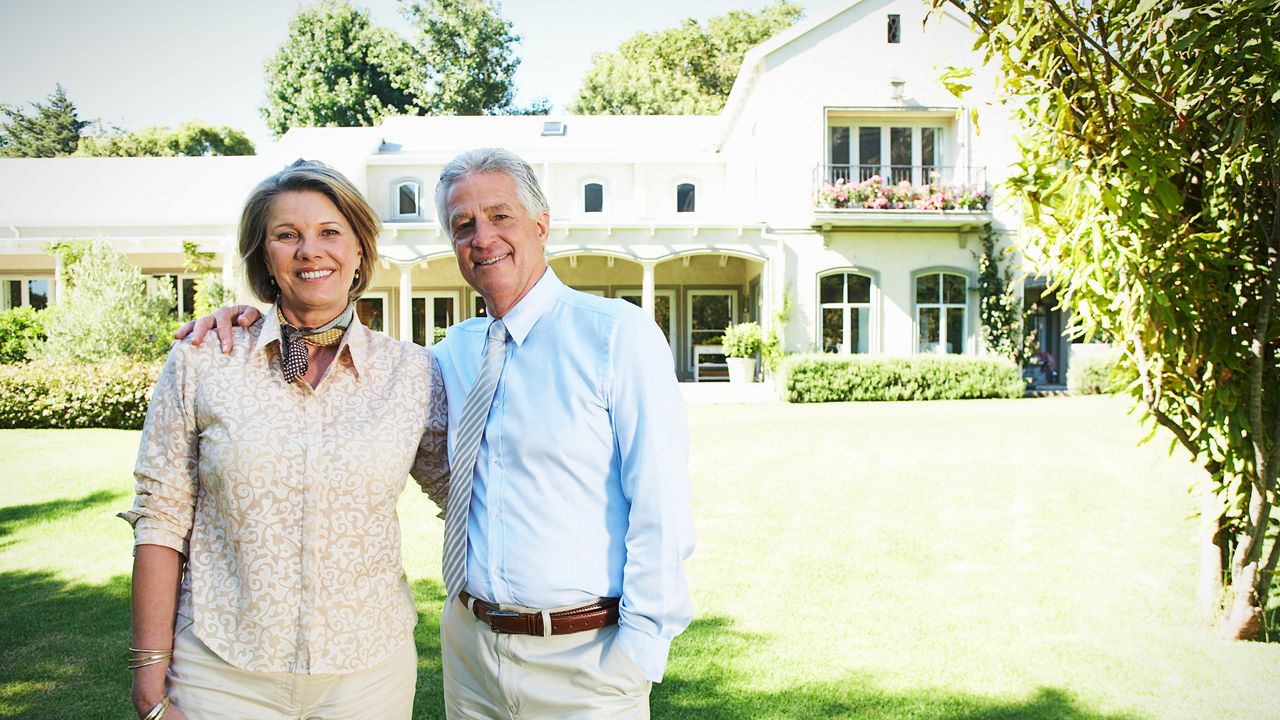 Boomer couple in front of house