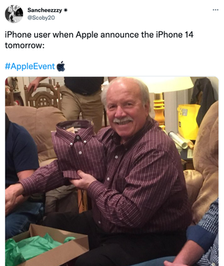 A man unwraps a shirt identical to the one he is wearing