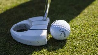 A putter is lined up behind the Callaway Supersoft Golf Ball