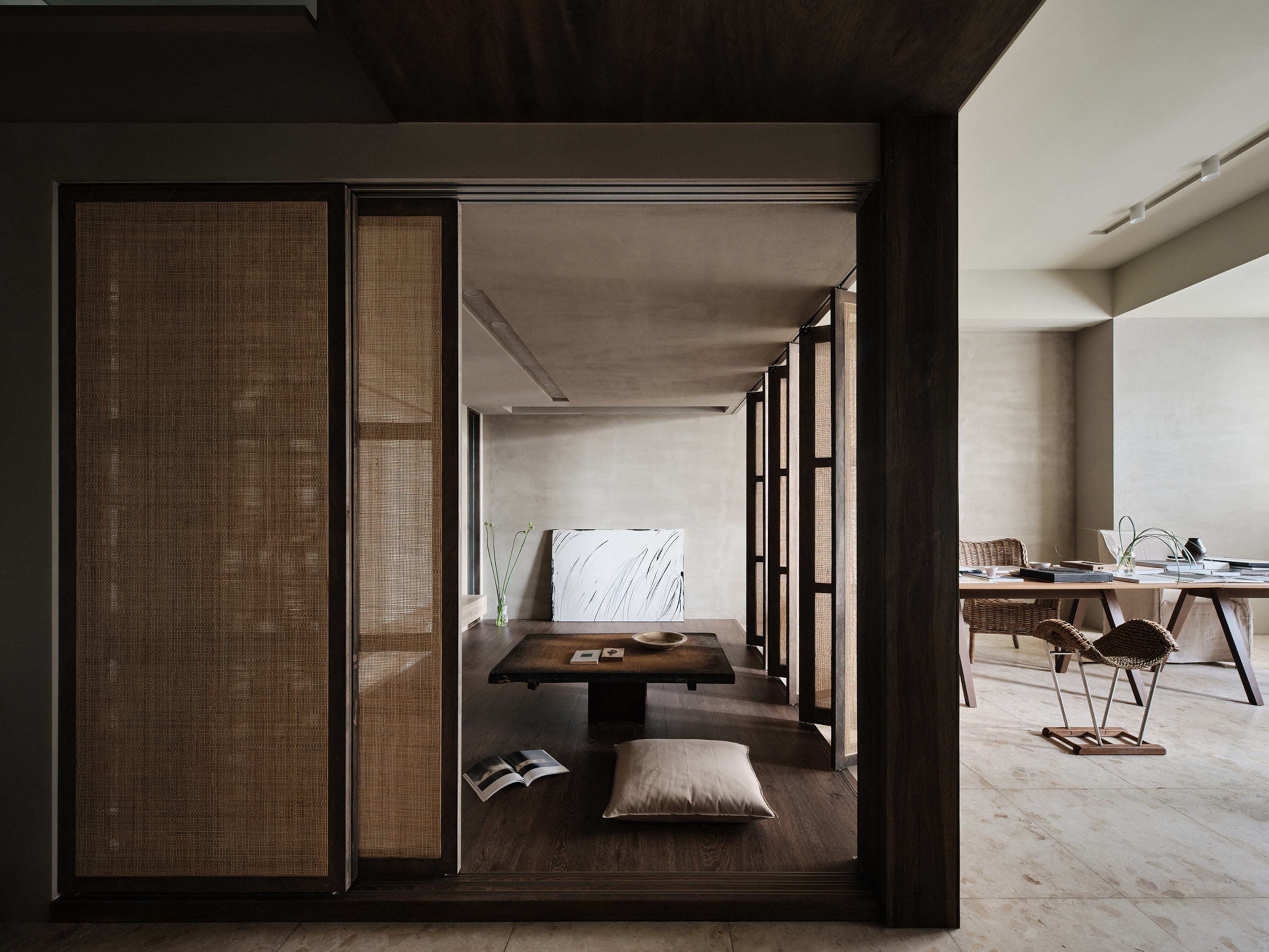 An open-plan room with rattan screen separating a meditation space from the rest of the home in all neutral tones