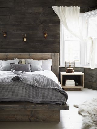 rustic wooden platform bed in bedroom with wood wall cladding by Rust Collections