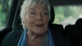 An older woman smiling in the back of a car