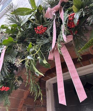 Christmas foliage design above doorway with pink velvet bows and red berries