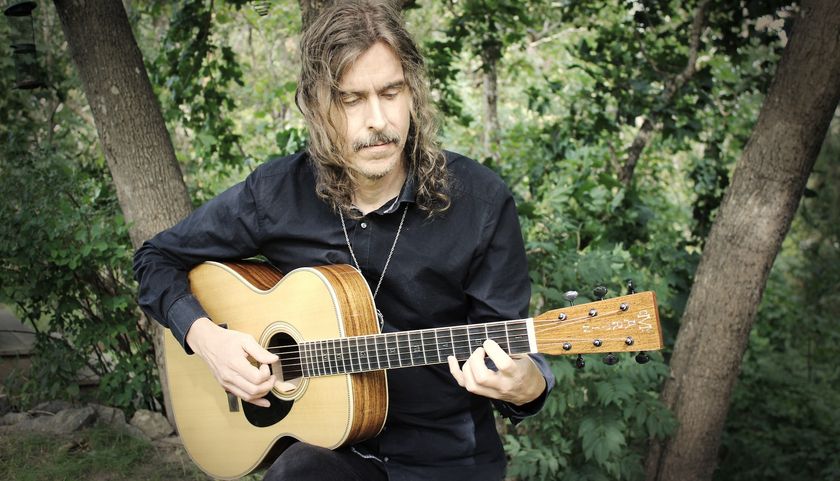 Mikael Åkerfeldt plays his new signature Martin acoustic guitar, with lush greenery behind him