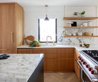 Modern white kitchen with wooden accents and open plan shelving in place of upper cabinets in place of upper kitchen cabinets and wooden lower cabinet fronts and kitchen island