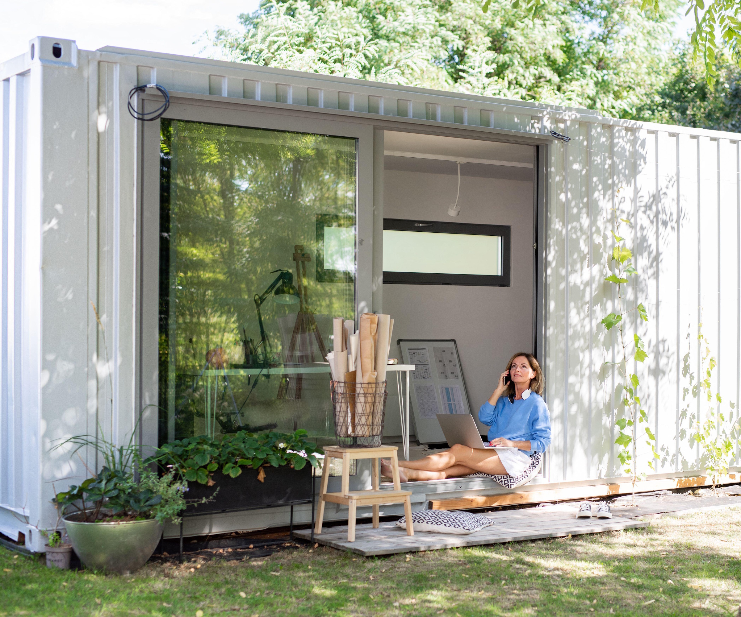Woman working in home office in container house in backyard