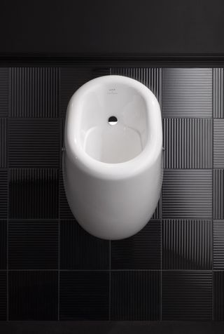White urinal on dark tiled wall