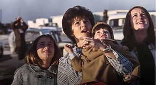 A woman and her three children raise their eyes to the sky