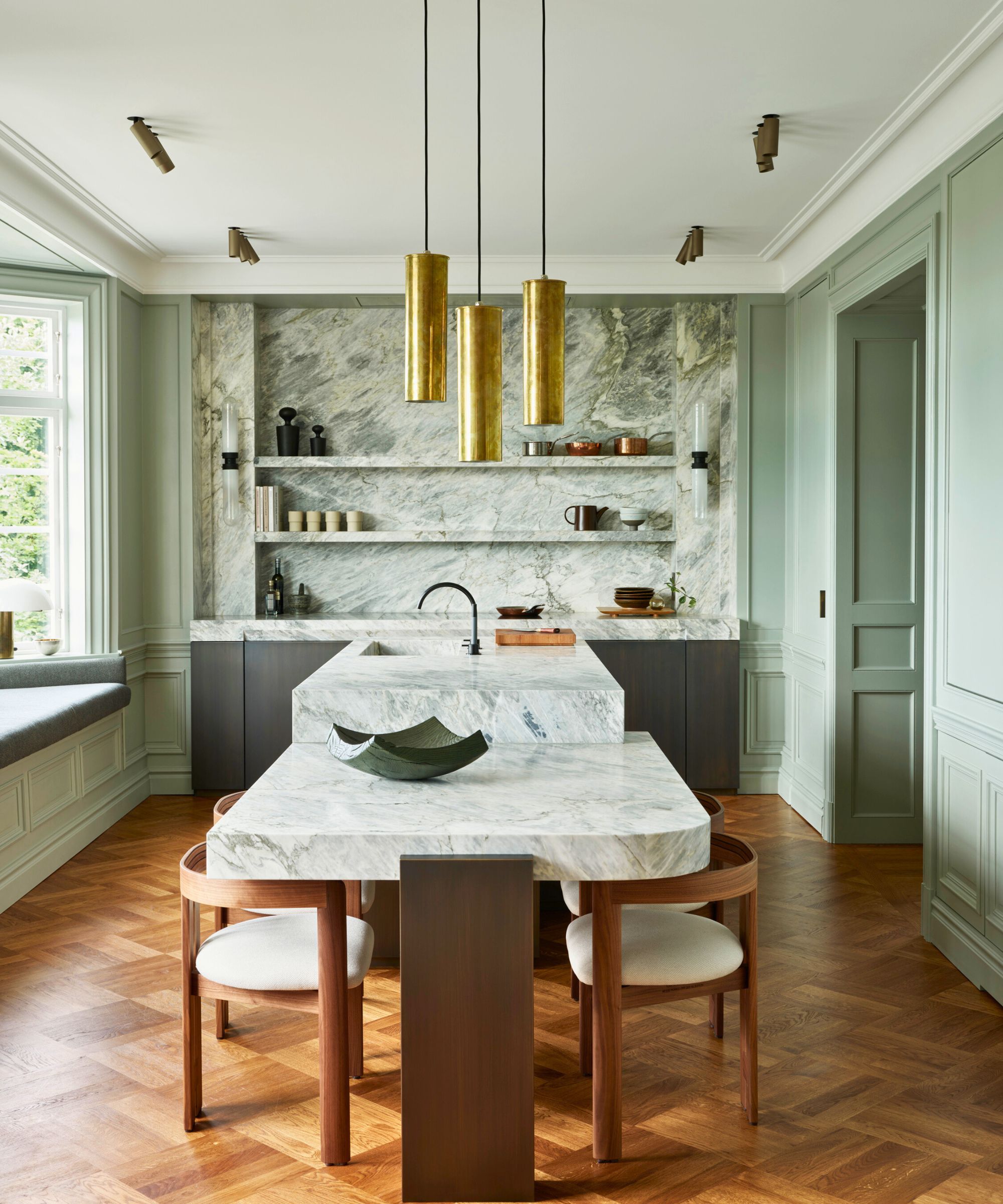 Kitchen with wooden floor green cabinets and marble island, countertops and backsplash