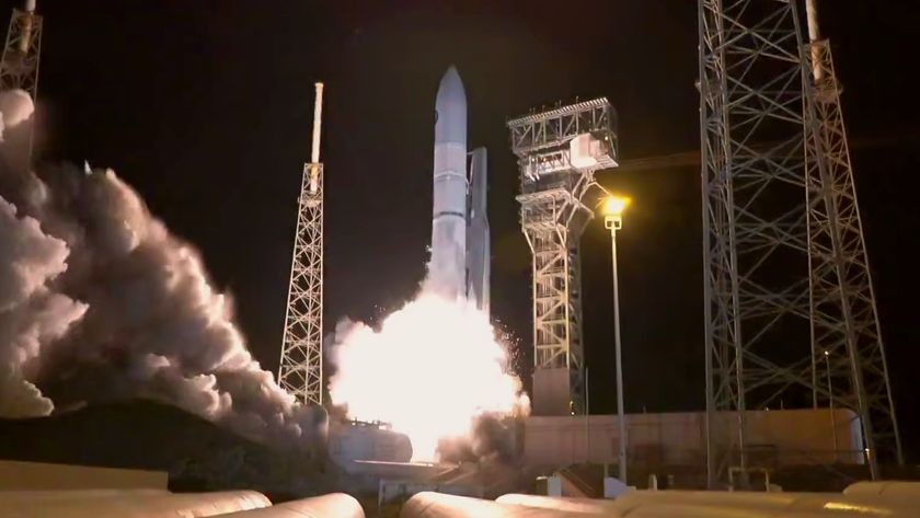 a white rocket lifts off from a launch pad at night.