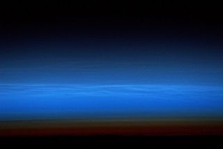 A wispy layer of mesospheric clouds illuminates Earth's atmosphere in this photo taken from the International Space Station. European Space Agency astronaut Luca Parmitano tweeted this photo from space, writing, "Mesospheric clouds tinge the sunset, south of the Indian Ocean." Mesospheric clouds, also known as noctilucent clouds, form 47 to 53 miles (76 to 85 kilometers) above Earth's surface, an altitude where water vapor can freeze into clouds of ice crystals. For comparison, the International Space Station orbits at an average altitude of 250 miles (400 km).