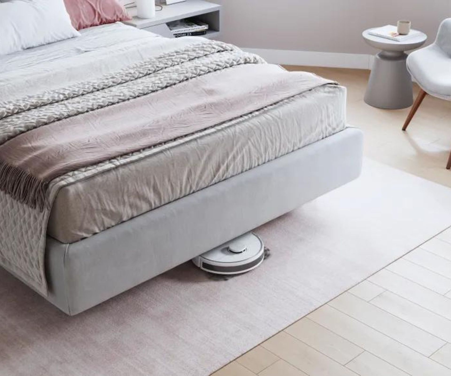 An ECOVACS robot vacuum cleaning beneath a bed.
