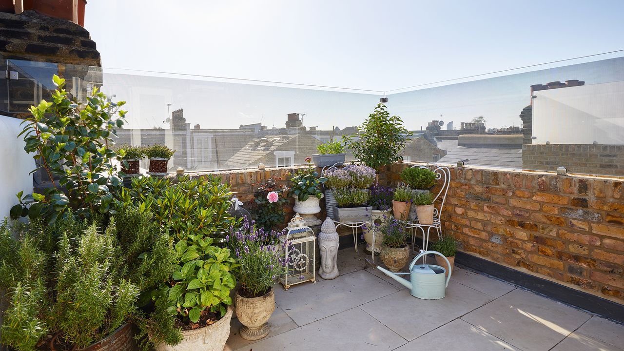 Balcony with brick and glass walls and selection of potted plants