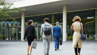 Return to office concept image showing workers walking toward office entrance.