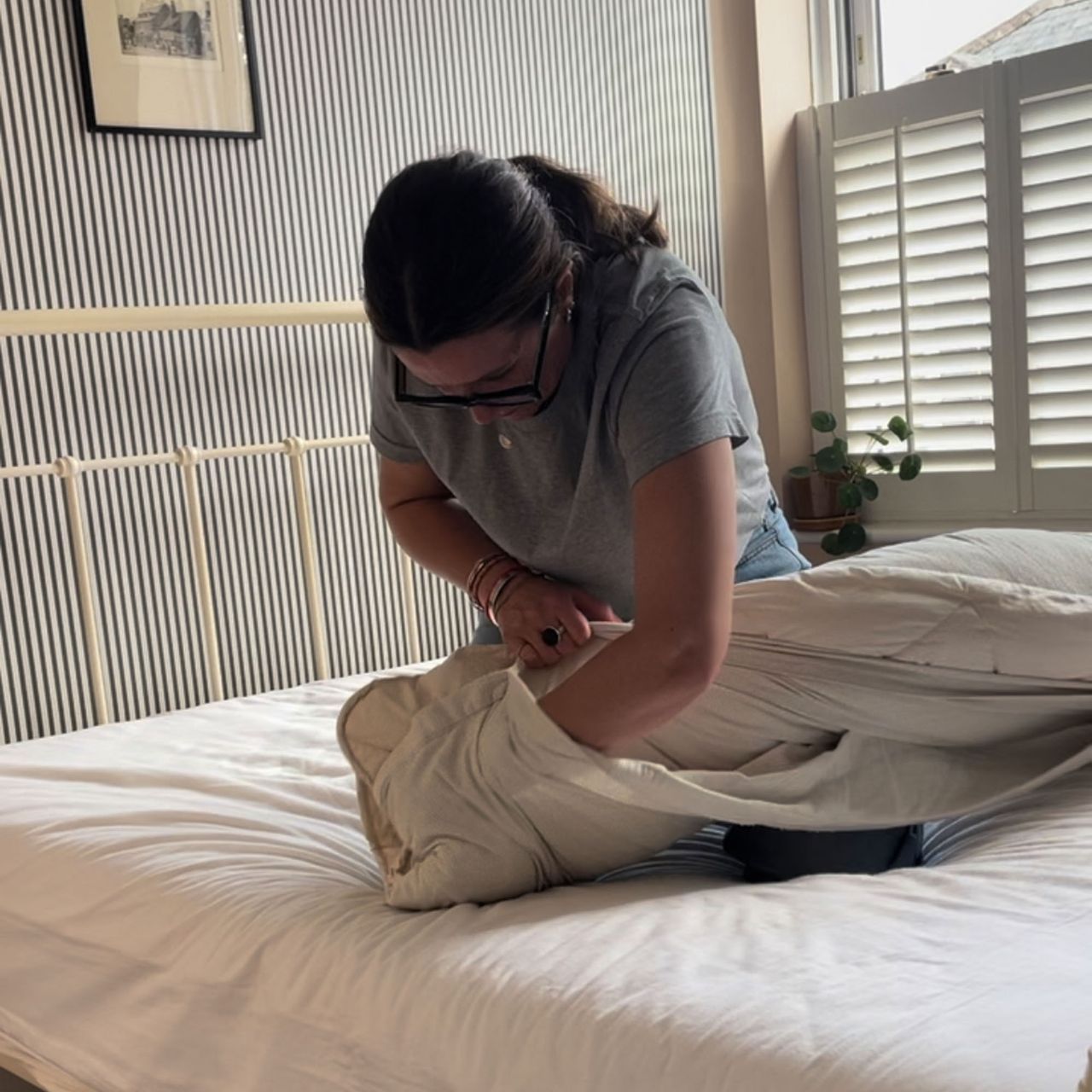 A woman putting a duvet cover onto a duvet using the 'burrito' method