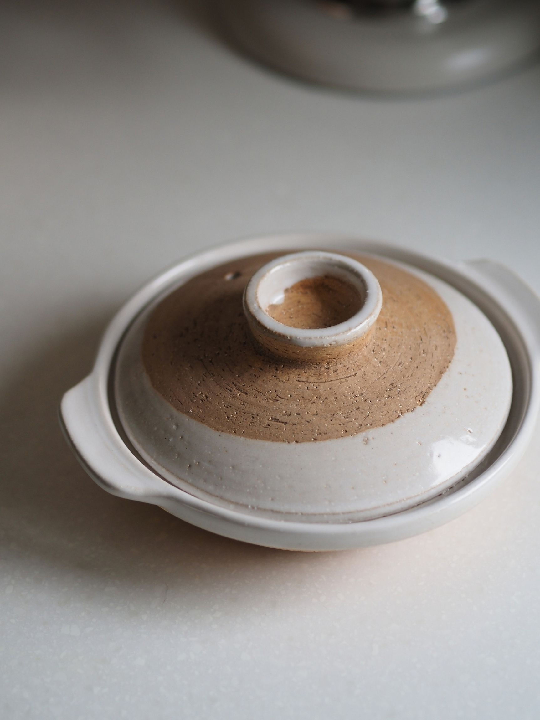 a japanese donabe with decorative glazes in a neutral kitchen
