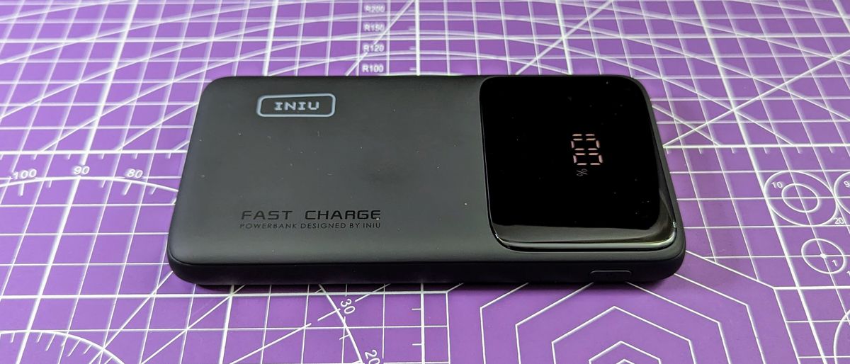 Iniu B6 power bank from the side, showing 100% capacity, and on a purple background. 