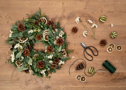 Christmas wreath being made with ingredients and tools shown