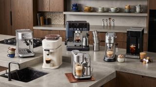 6 coffee machines arranged on a kitchen counter top.