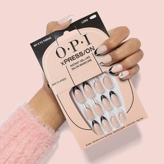 model's hands wearing opi press on nails and holding the press on box