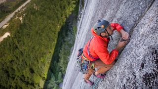 A climber in a red jacket climbing a crack