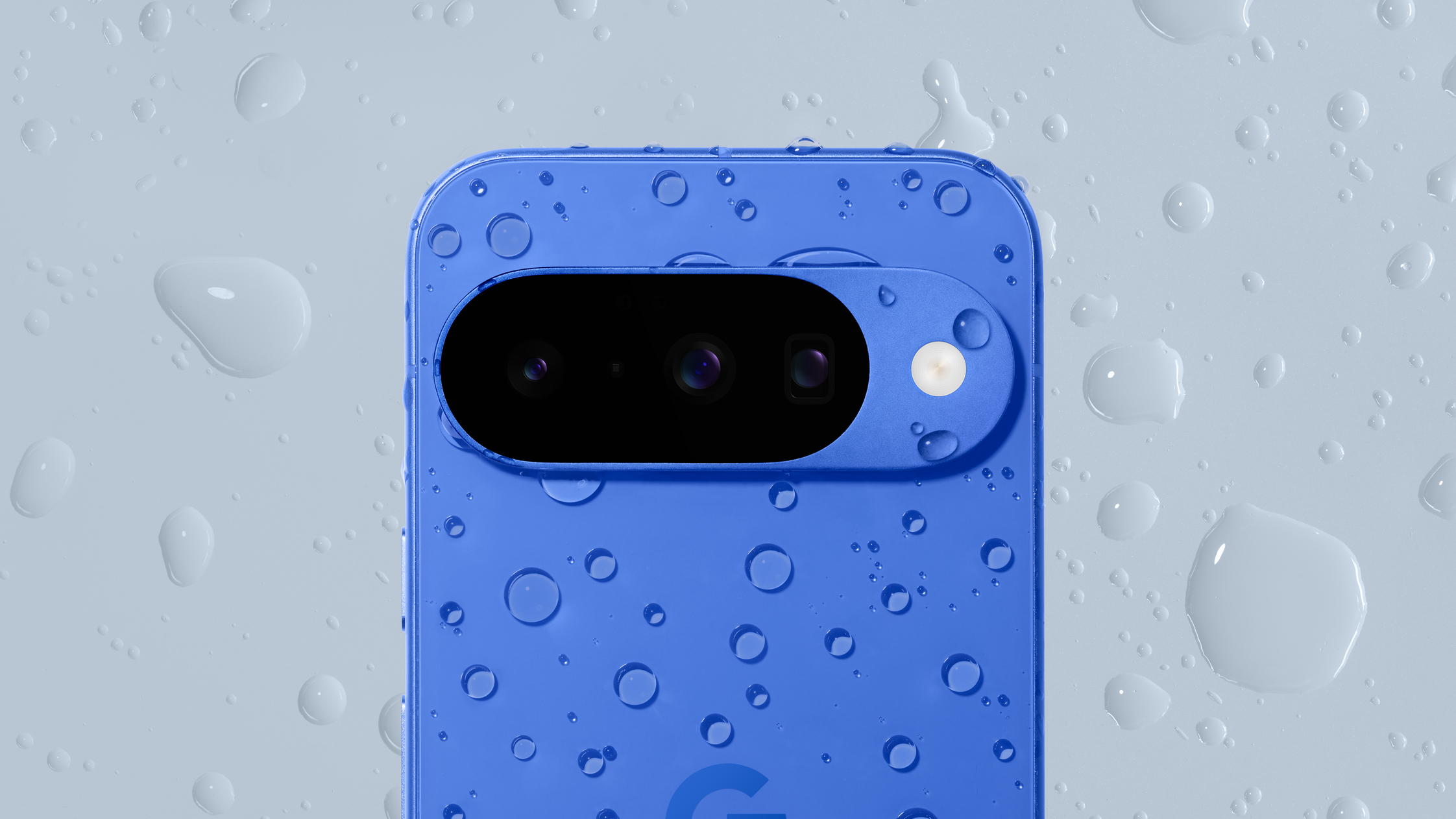 The Google Pixel 10 in blue, covered in water droplets