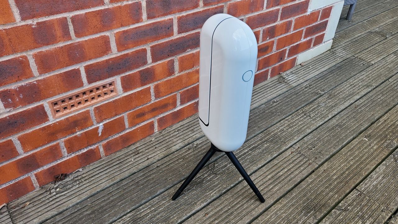 Image of the Vaonis Vespera Observation Station. It's a sleek white capsule balanced on a black tripod. It's facing forward, slightly to the right. There is the outline of a blue circle which is a button near the top of the item. The telescope/camera arm is closed at the moment.