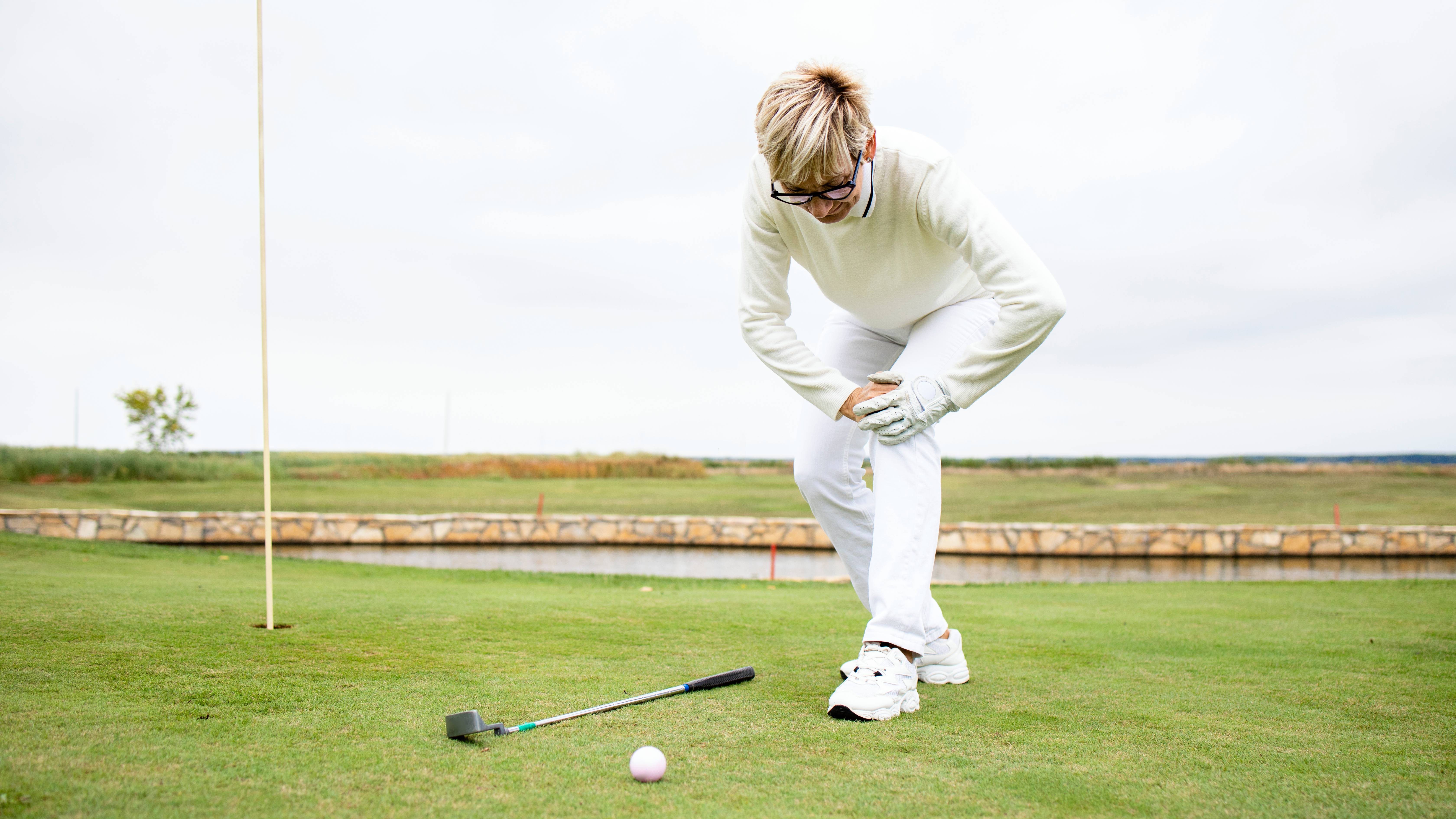 Female golfer holding her injured knee