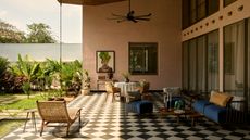An outdoor space with black & white chequerboard flooring, and plaster walls 