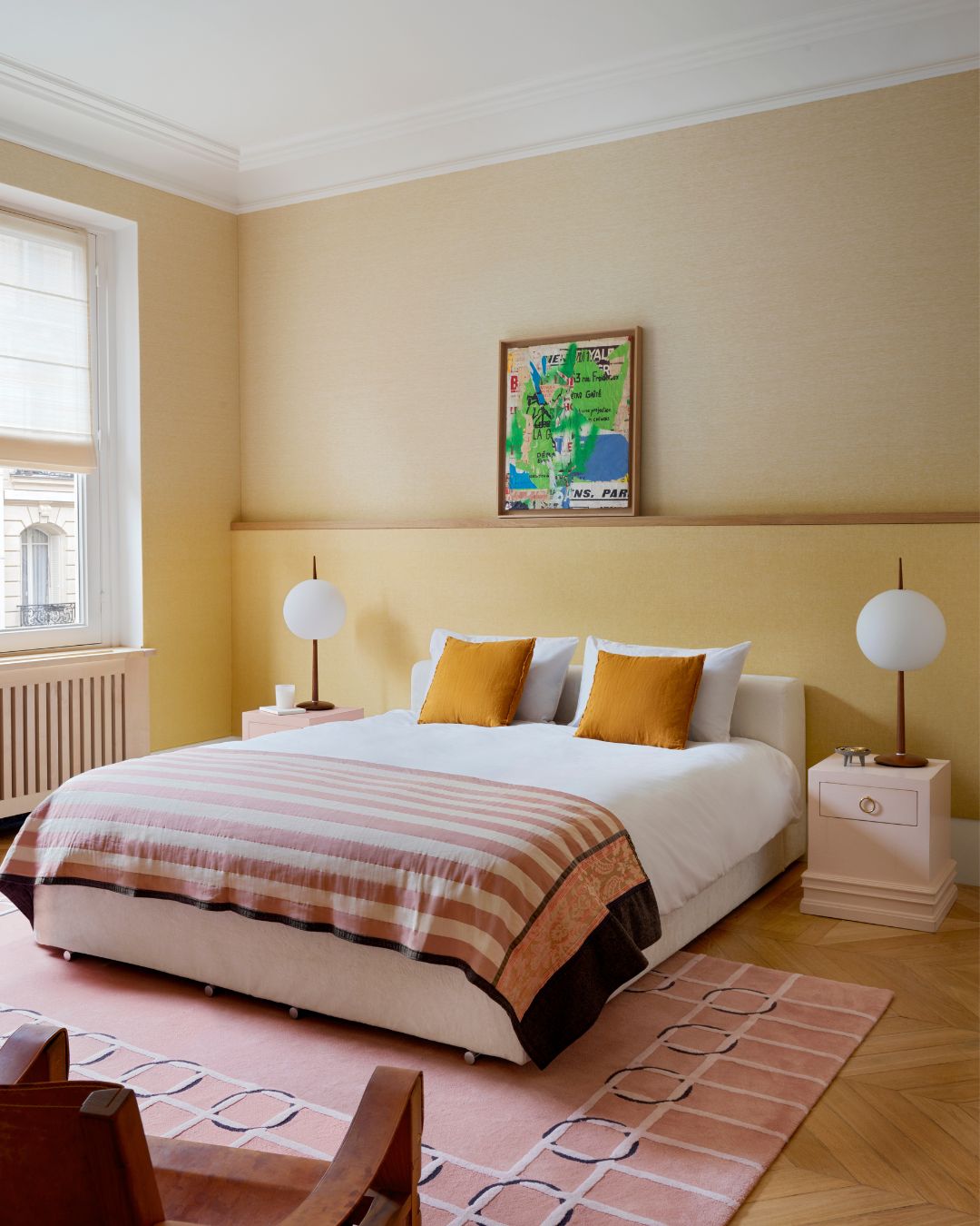 A bedroom with yellow walls, two small pink side tables and a pink rug