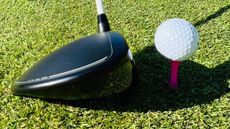 Driver addressing ball on pink 'castle' tee