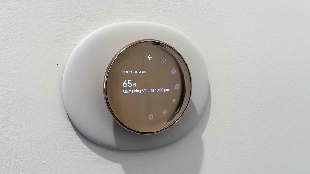 Google Nest Learning Thermostat in Polished Gold colorway mounted on wall, showing size of mountain panel in relation to the thermostat