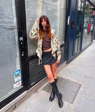 French woman wearing jacket, black miniskirt, and tall black boots