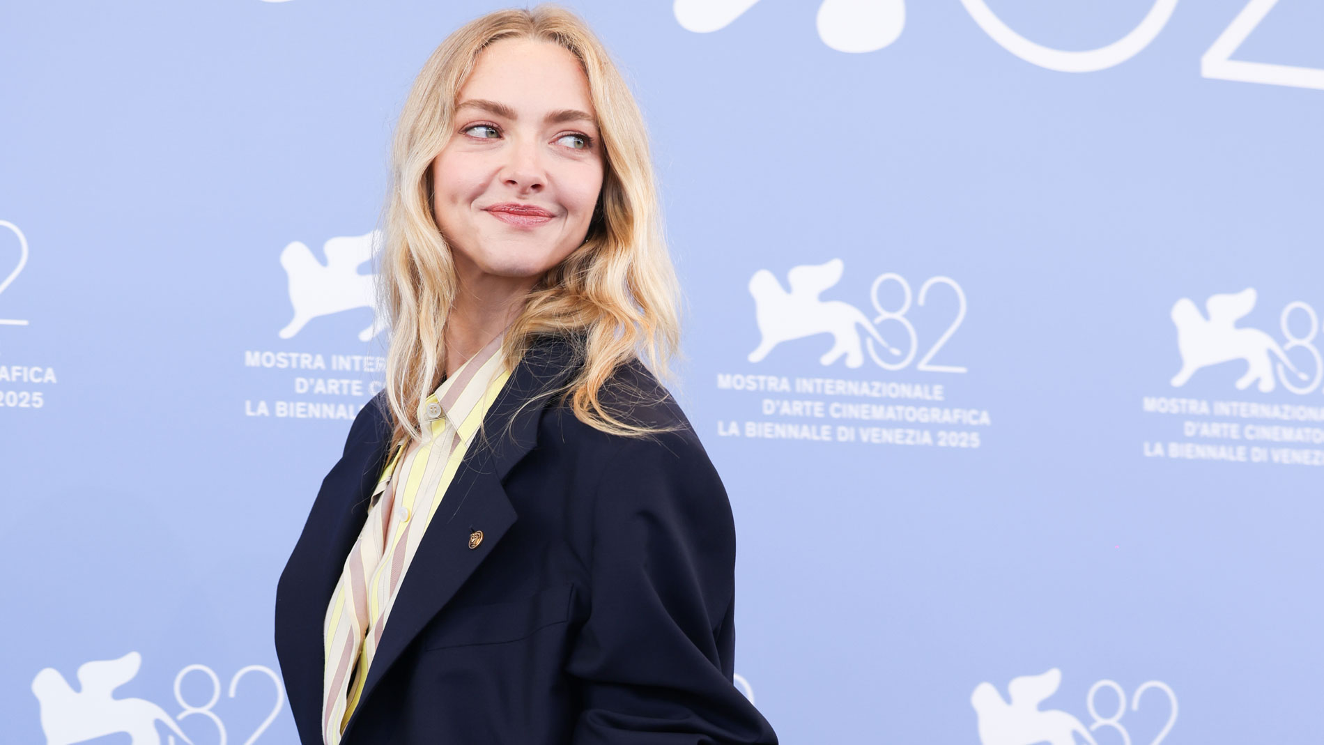 Amanda Seyfried looks over her shoulder wearing a blazer