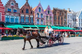 Tourists being taken on city tour with a horse and trap in the Markt Square, Bruges