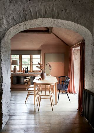 Soft terracotta walls in dining room with furniture by Ercol