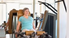 woman in a turquoise tshirt on a leg curl machine in a gym setting 
