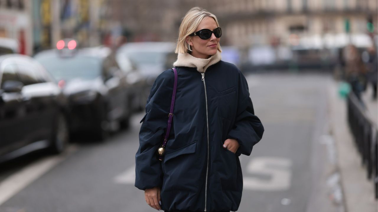 A woman with a blonde bob wearing an autumnal outfit and scarf