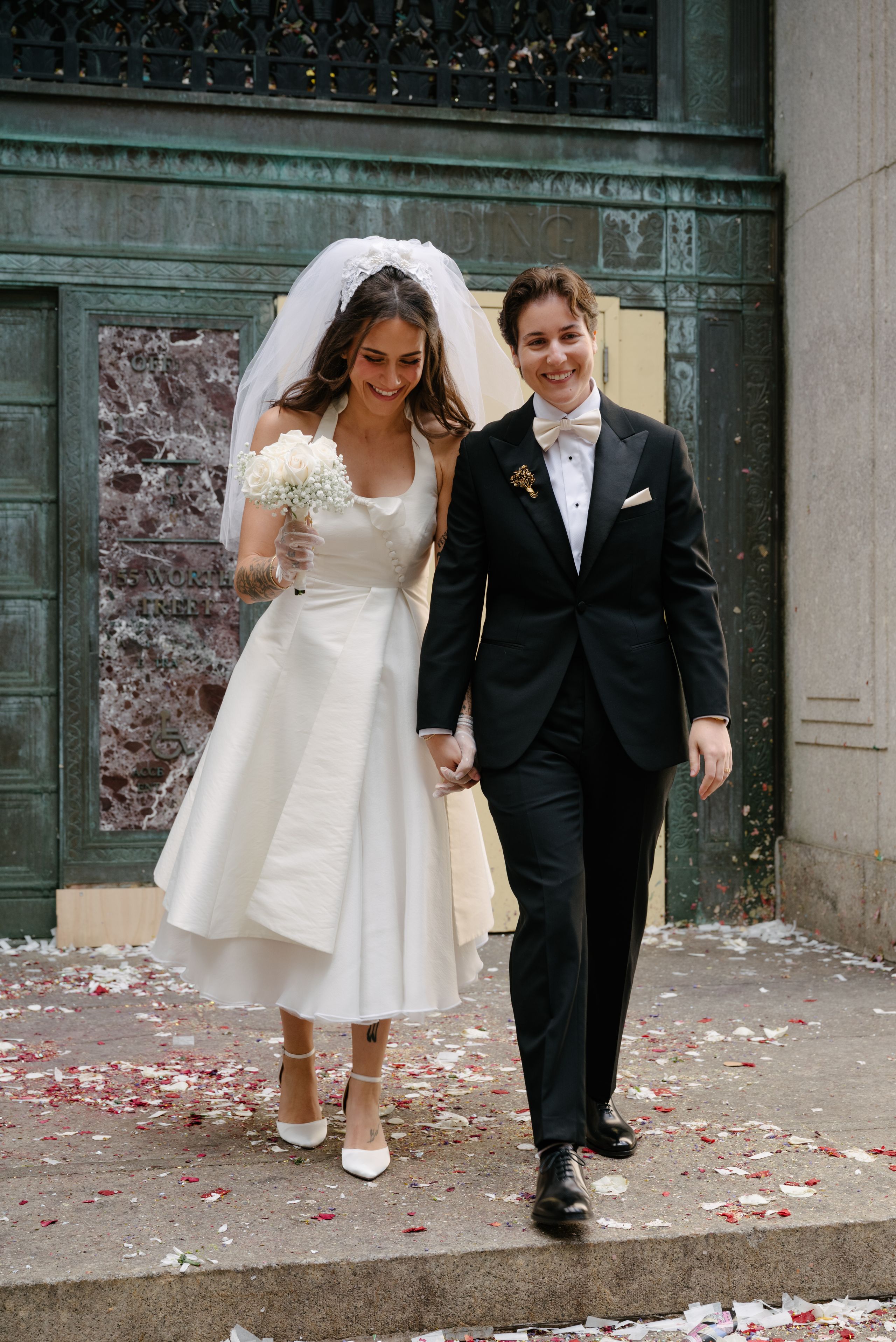 Stevie Barbieri holding hands with her partner wearing a vintage bridal look.