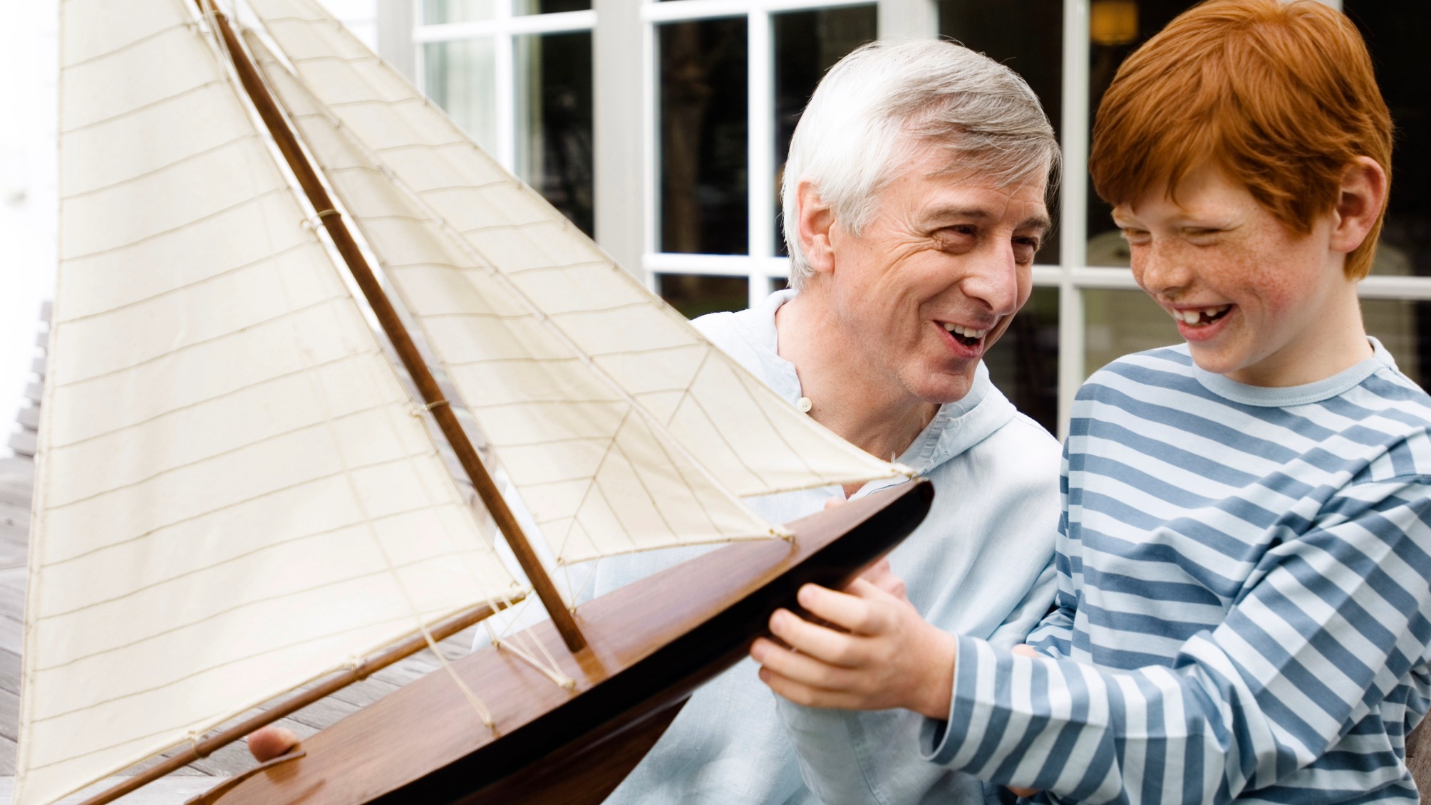 Grandfather and grandson hold a model sailing boat