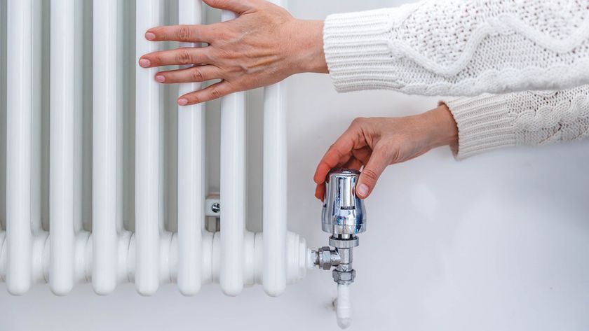 white column radiator with woman&#039;s hands adjusting thermostat